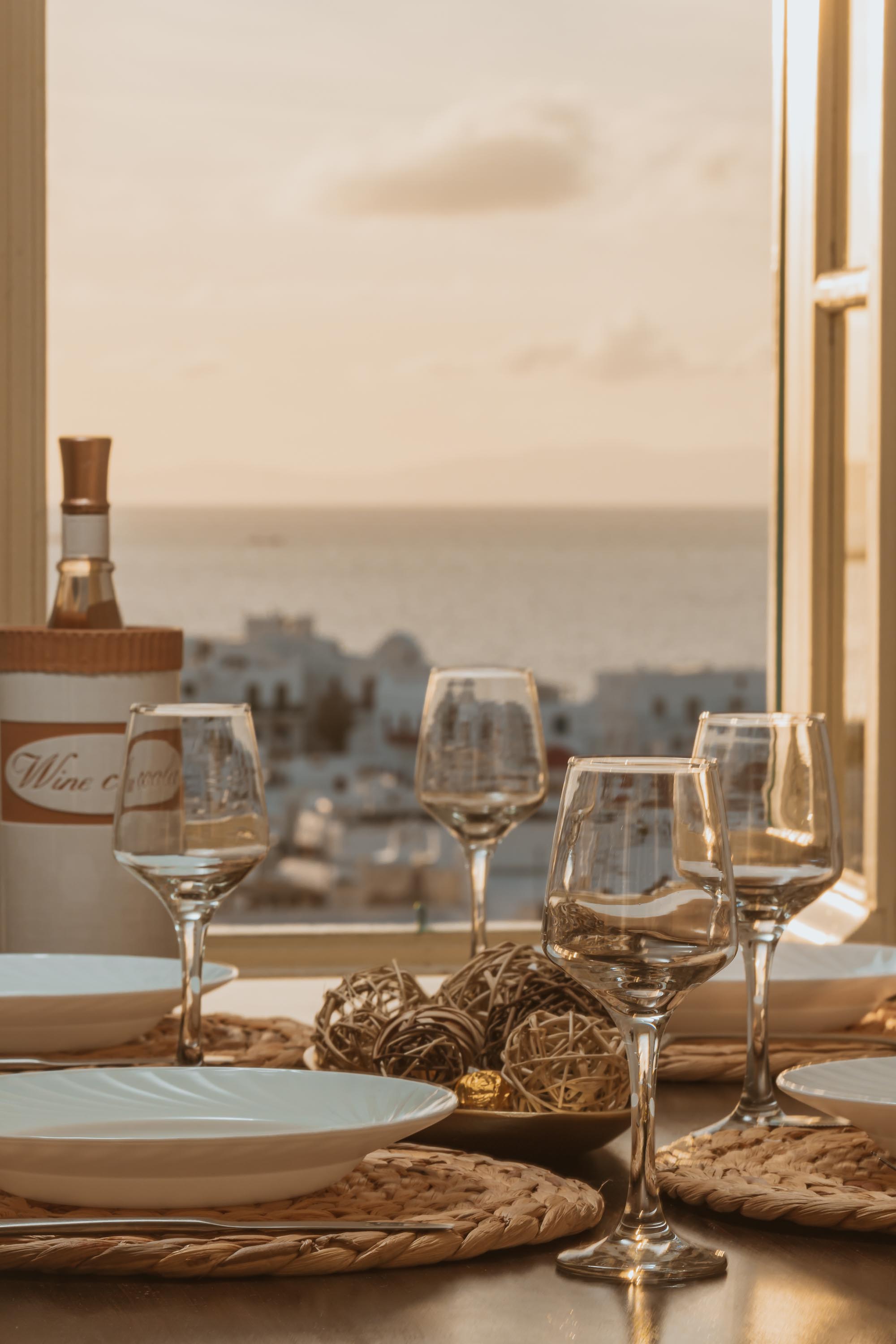 Dining table with wine glasses and sea view at golden hour